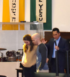 Pastor Nick Kim prays for Darren and Abigail, VBS co-directors.