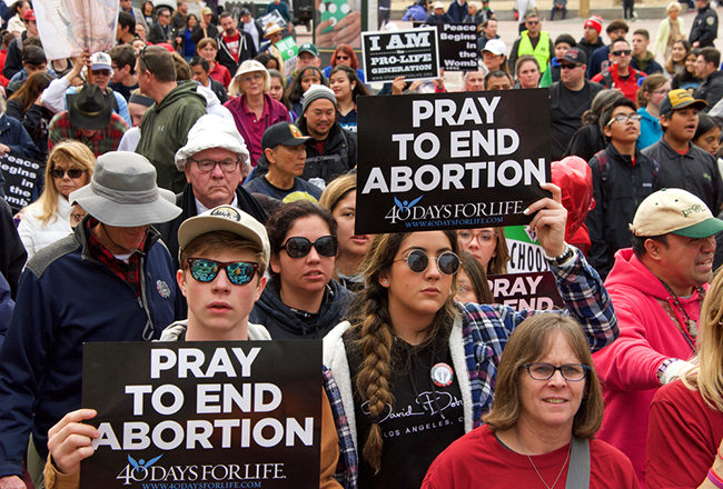 Unidentified participants at the 16th annual Walk for Life marching down Market street holding pro life signs and banners.