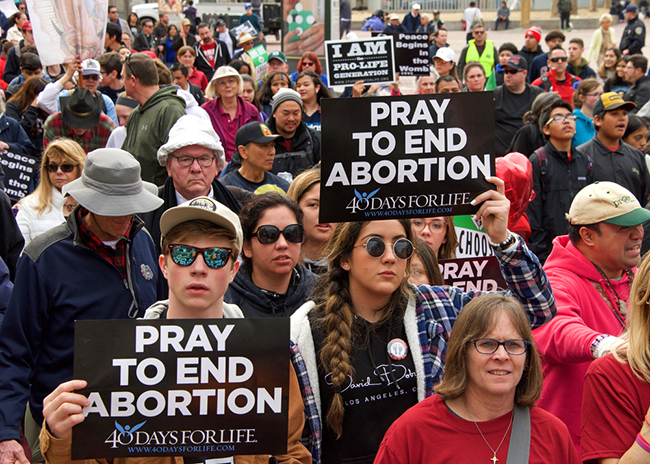 Unidentified participants at the 16th annual Walk for Life marching down Market street holding pro life signs and banners.